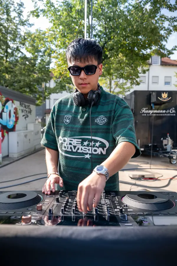 DJ Dang mit Sonnenbrille legt draußen am DJ-Pult auf