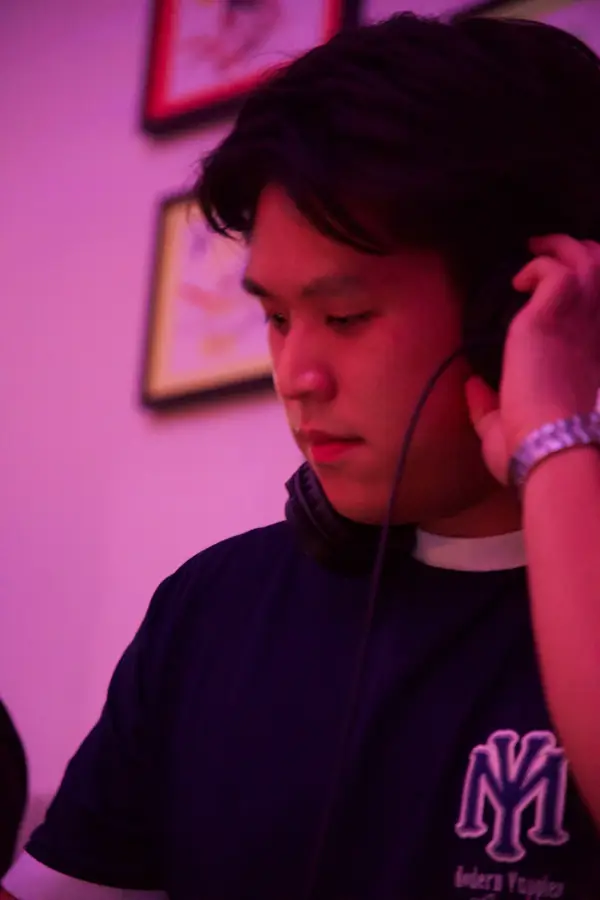 DJ Dang hält im pinken Partylicht den Kopfhörer ans Ohr