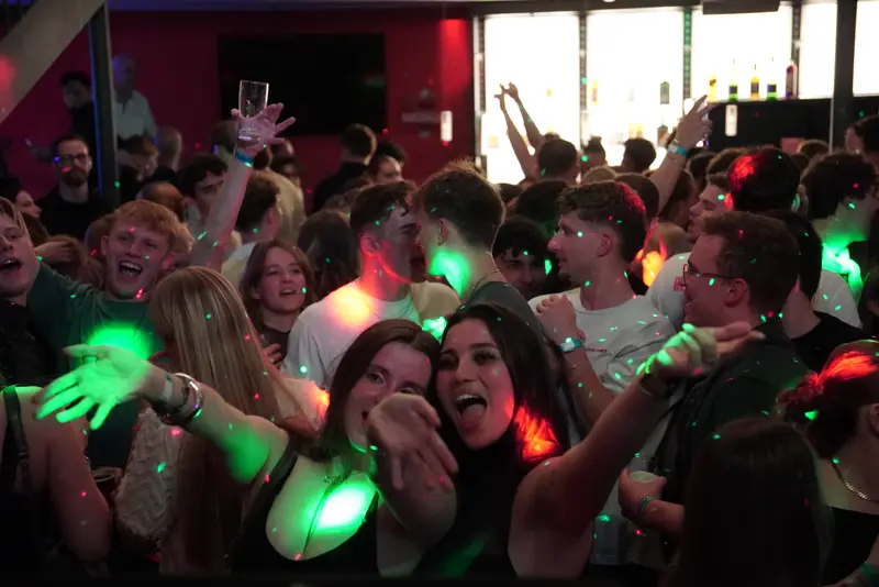 Volle Tanzfläche bei One Last Drink: Gäste feiern mit erhobenen Armen in grünem und rotem Licht